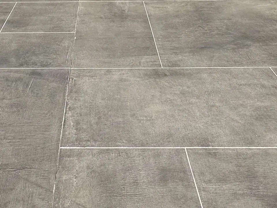 Close view of large-format ashlar-slate joints in a charcoal decorative concrete overlay.