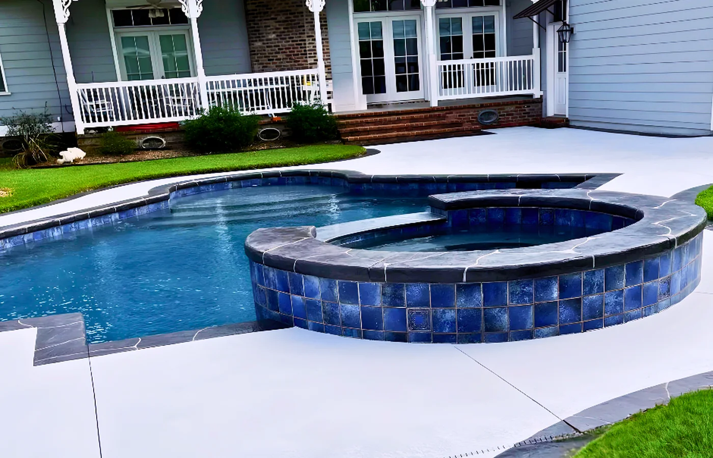 Completed textured concrete deck surrounding a blue pool and spa.