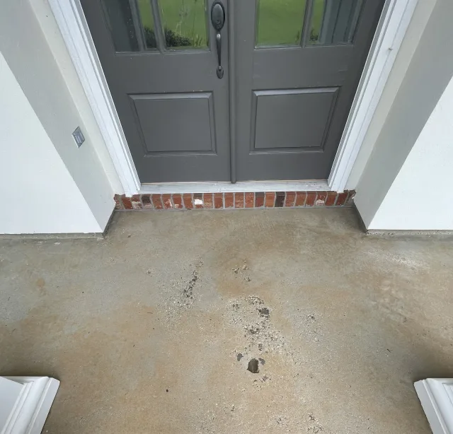 Damaged plain concrete porch at the same gray double doors before resurfacing.