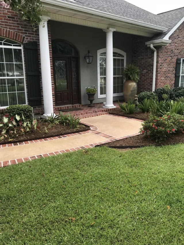 Brick-bordered front entry and walkway by Decorative Concrete of South Louisiana.