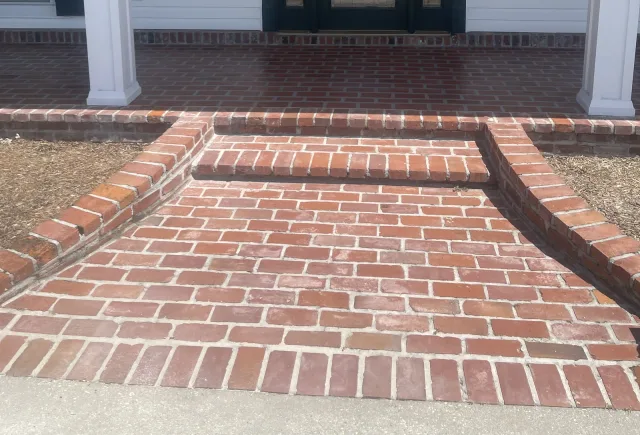 Brick-pattern porch surface meeting the existing brick steps and border.