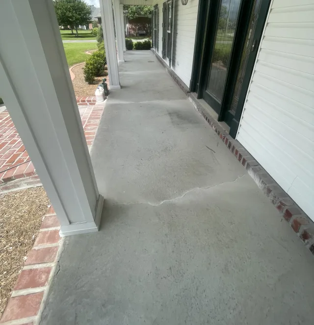 The same porch before resurfacing, with cracked gray concrete beside the white siding.
