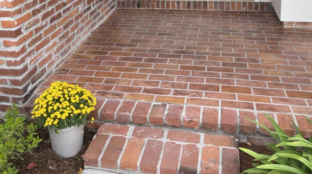 Brick-pattern porch surface meeting the existing brick steps at the entry.