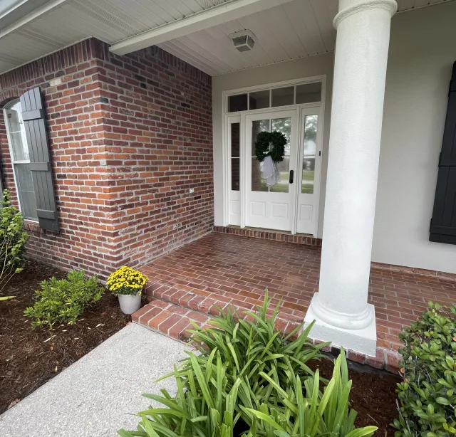 Brick-pattern porch with round columns by Decorative Concrete of South Louisiana.