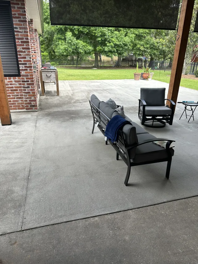 Plain gray concrete covered patio with outdoor furniture before the work.