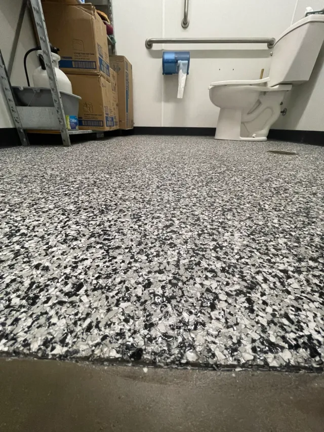 Close perspective of the black and white flake floor in the utility bathroom.
