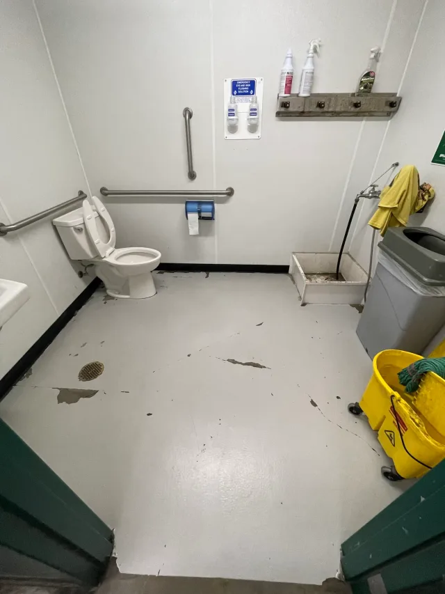 Worn white floor coating in the utility bathroom before refurbishment.