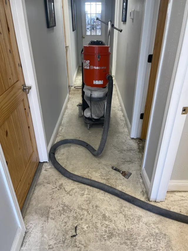 Floor preparation equipment and vacuum hose in the office entry corridor.