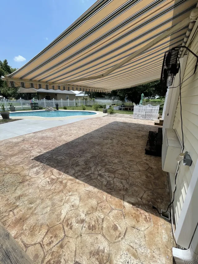 Existing stamped stone-pattern concrete under the awning before the work.