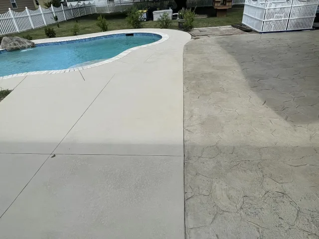 Pool deck mid-project, with the new light surface on one side and the old stamped pattern on the other.