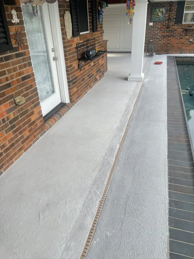 Existing deck surface along the pool and brick wall before the work.