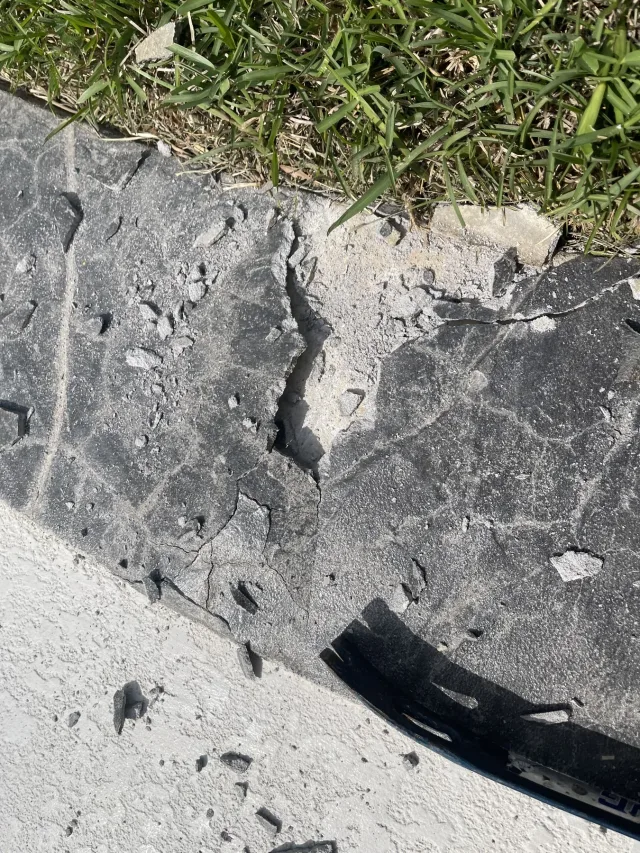 Close view of broken, deteriorated concrete at the pool edge.