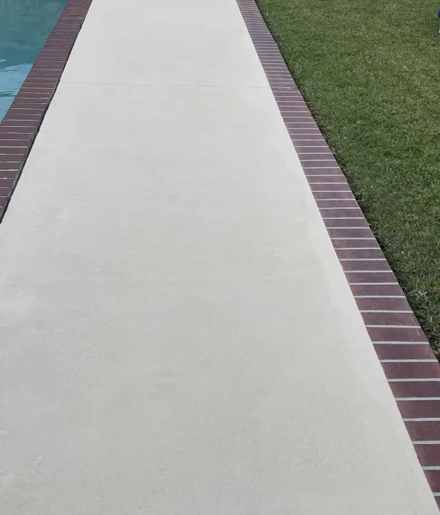 Clean finished deck between the pool coping and the grass.