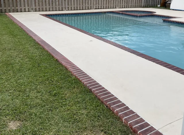 Finished deck and brick edge running beside the lawn.