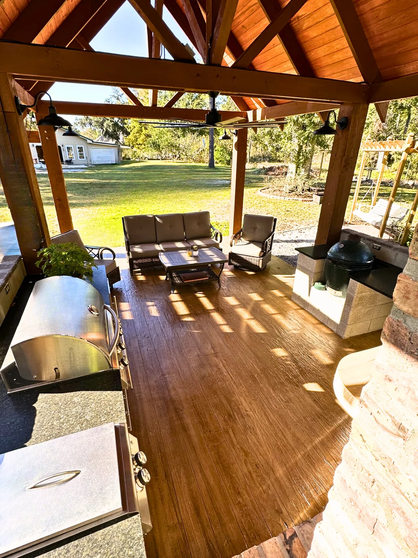 Wood-look decorative concrete floor across a covered outdoor kitchen and seating area.