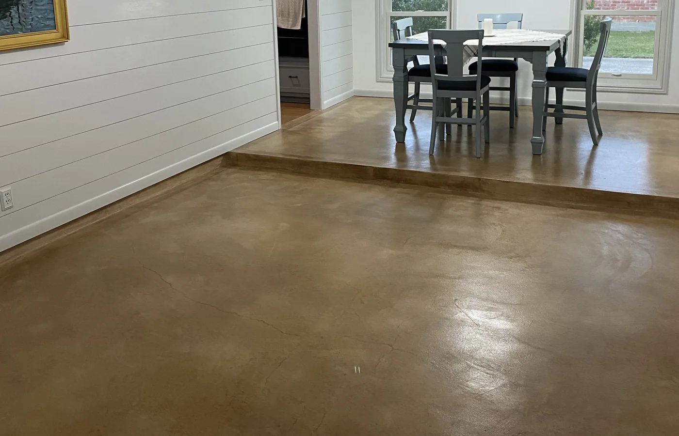 Stained concrete floor with natural neutral-brown variation across a finished interior room.